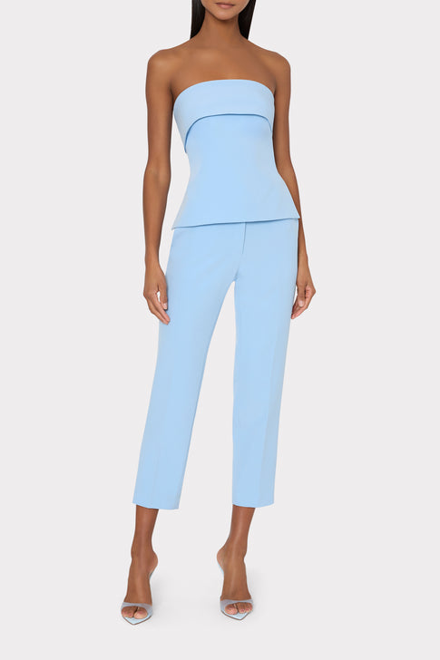Woman wearing a light blue strapless top and pants on a white background