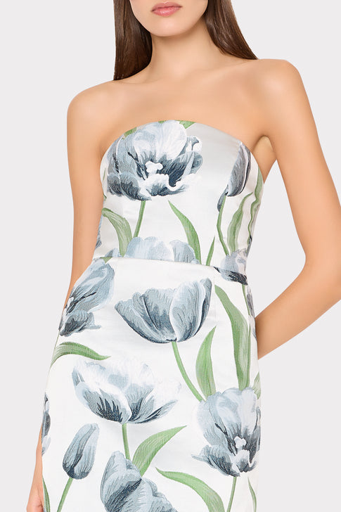 Woman wearing a strapless dress with floral pattern on a plain background