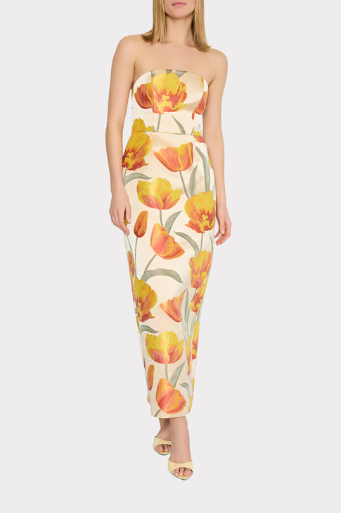 A strapless maxi dress with a floral pattern featuring primarily yellow and orange tulips on a beige background.