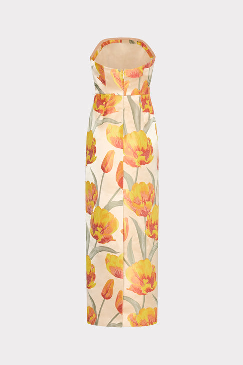 A strapless maxi dress with a floral pattern featuring primarily yellow and orange tulips on a beige background.