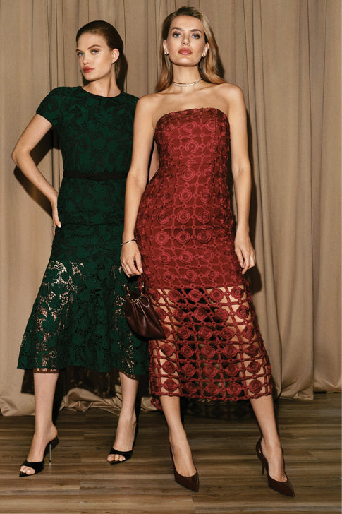 Two women wearing elegant dresses standing against a neutral background